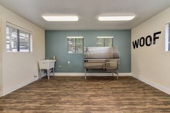 Dog Spa Tub with Hardwood Inspired Floor, Dog Washing Tub, WOOF Written in Black Letters on Wall, and Fluorescent Lights